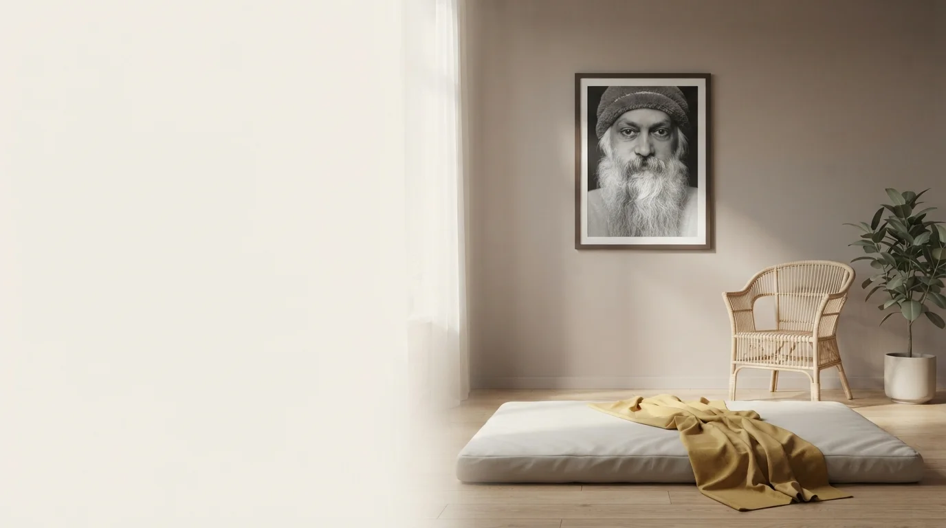 Ein menschenleerer Massageraum mit Bodenmatratze, Korbsessel, gelber Decke und einem gerahmten Schwarz-Weiß-Porträt von Osho.